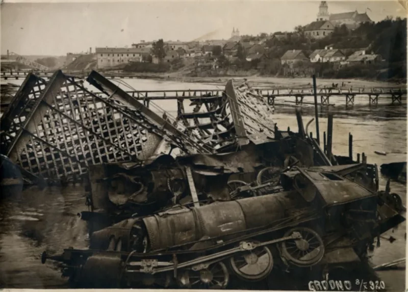8.10.1920, Гродна. Разбураны чыгуначны мост праз Нёман, на заднім плане драўляны мост, пабудаваны польскімі сапёрамі, на пярэднім плане лакаматыў які сышоў з рэек цягніка, які ляжыць у вадзе. Фота: Hrodna 11:27