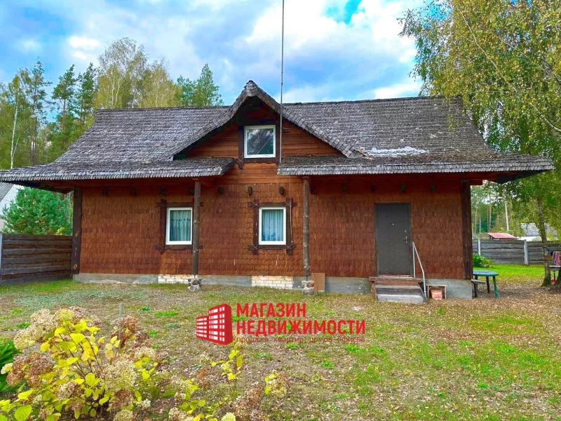 Нерухомасць тыдня: пад Гроднам прадаюць хутар з відам на Нёман і сасновы лес Хутар у вёсцы Загорнікі пад Гроднам. Драўляны дом з саламяным дахам, акружаны дрэвамі і травяністым дваром.